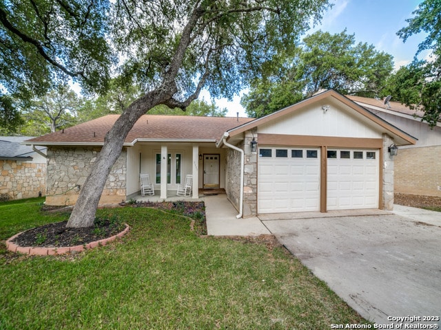 single story home with a front yard, a garage, and a porch