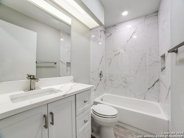 full bathroom with wood-type flooring, tiled shower / bath, vanity, and toilet