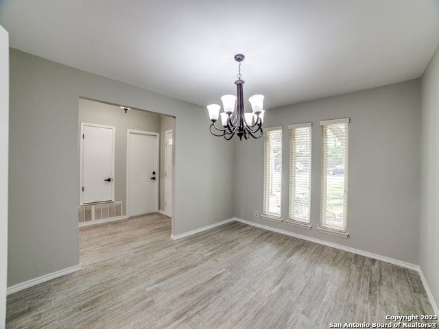 unfurnished room featuring light hardwood / wood-style floors and a chandelier