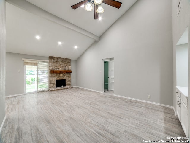 unfurnished living room featuring high vaulted ceiling, ceiling fan, light hardwood / wood-style floors, beam ceiling, and a fireplace