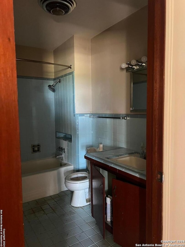 full bathroom featuring tile flooring, tile walls, tiled shower / bath combo, toilet, and vanity