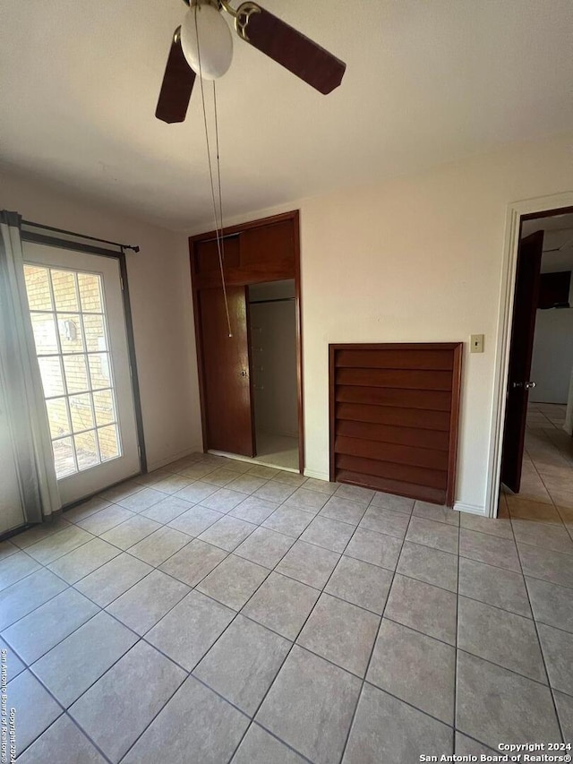 unfurnished bedroom with a closet, ceiling fan, and light tile flooring