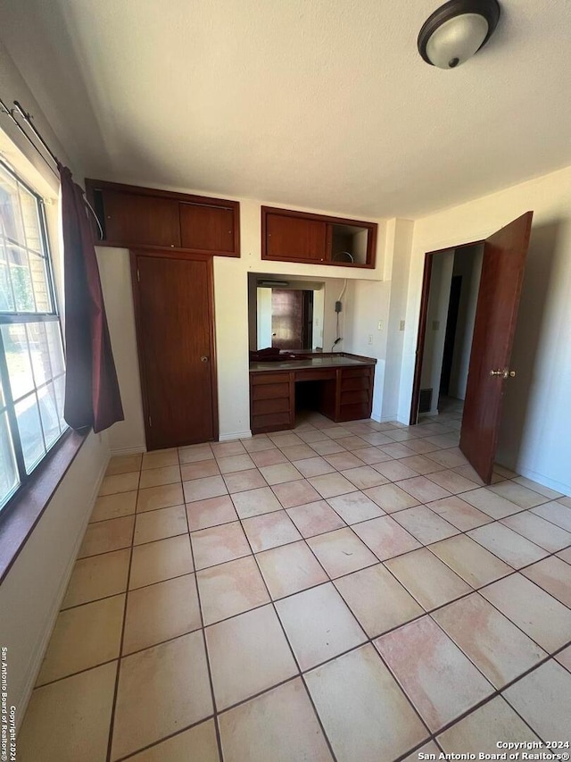 unfurnished bedroom featuring light tile floors and multiple windows