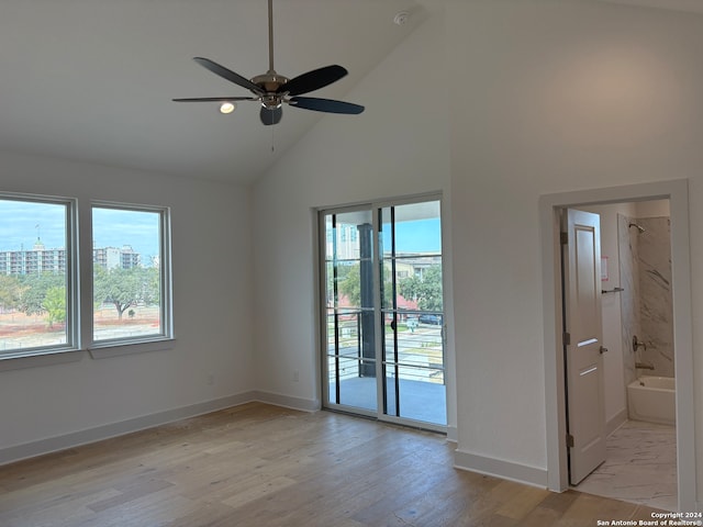 empty room featuring light hardwood / wood-style floors, high vaulted ceiling, and ceiling fan