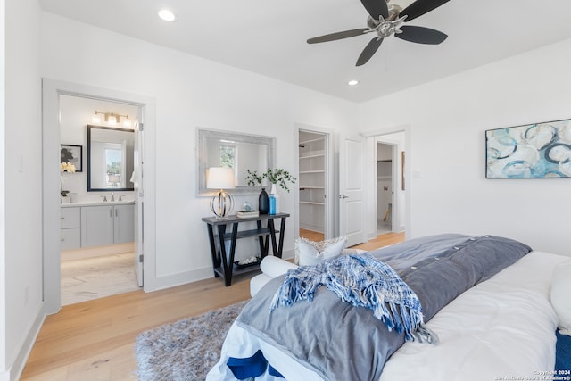 bedroom featuring ensuite bathroom, light wood-type flooring, a walk in closet, a closet, and ceiling fan