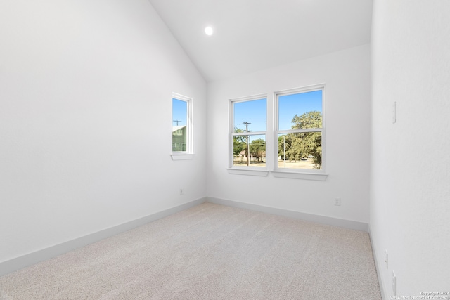 carpeted empty room featuring vaulted ceiling