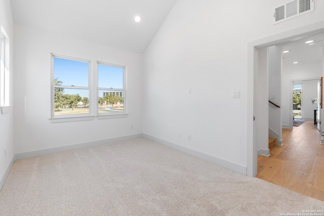 spare room with a healthy amount of sunlight, wood-type flooring, and vaulted ceiling