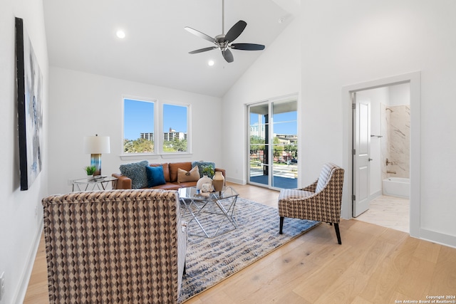 living room with light wood-type flooring, high vaulted ceiling, and ceiling fan