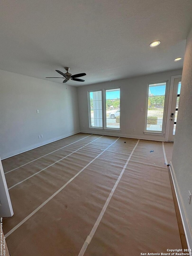 unfurnished room with a textured ceiling, wood-type flooring, and ceiling fan