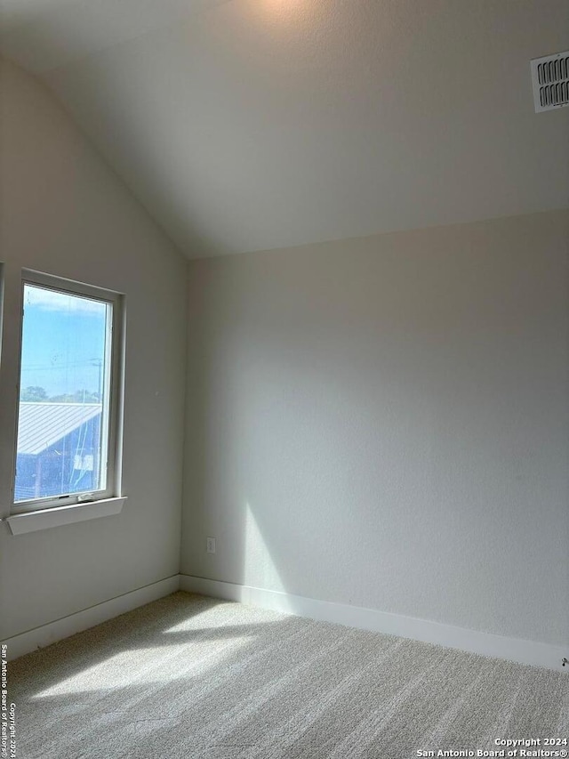 carpeted empty room featuring lofted ceiling