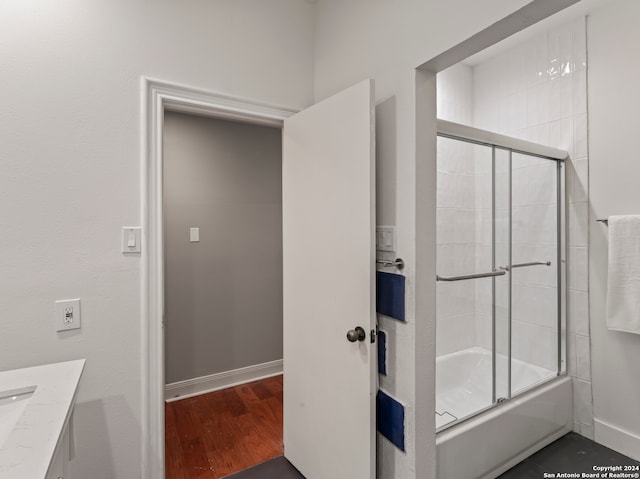 bathroom with vanity, hardwood / wood-style flooring, and shower / bath combination with glass door