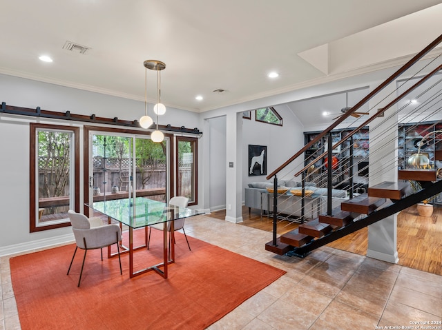 dining room featuring light hardwood / wood-style floors, a barn door, and ornamental molding