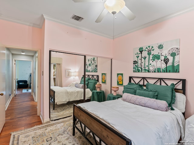 bedroom with ornamental molding, a closet, wood-type flooring, and ceiling fan