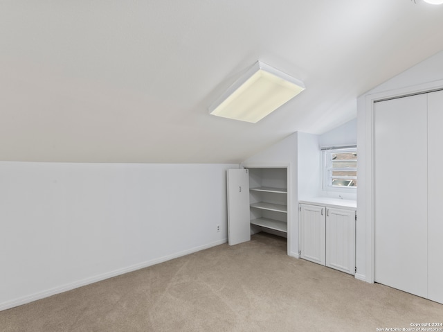 bonus room with lofted ceiling and light colored carpet