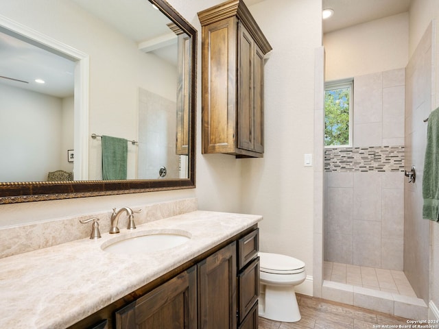 bathroom featuring toilet, vanity, and a tile shower