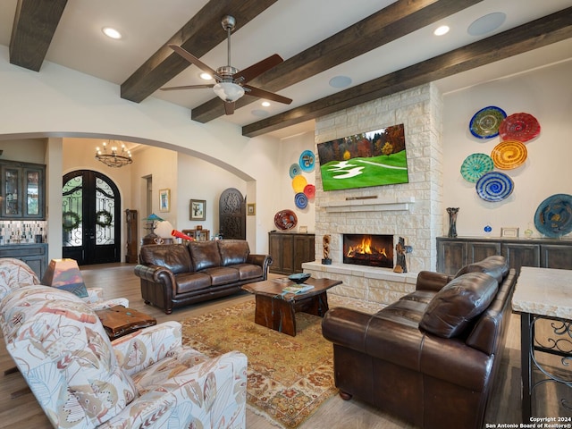 living room with hardwood / wood-style floors, beam ceiling, ceiling fan with notable chandelier, and a fireplace