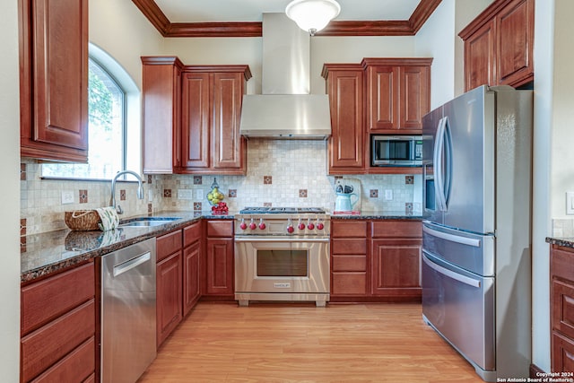 kitchen with light hardwood / wood-style floors, appliances with stainless steel finishes, wall chimney range hood, and sink