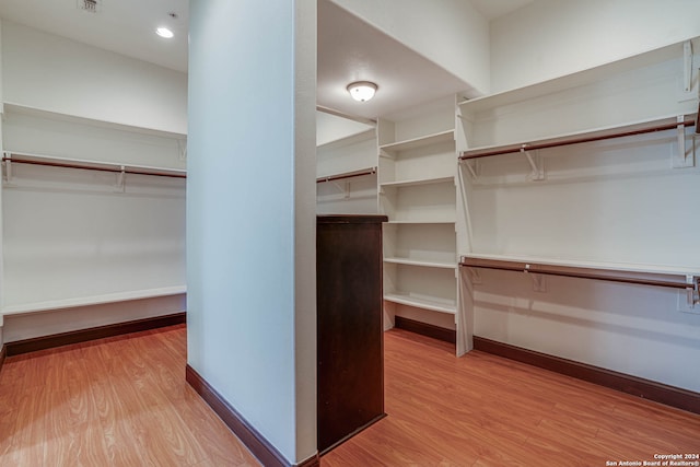 walk in closet with light hardwood / wood-style flooring