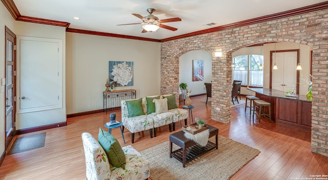 living room with hardwood / wood-style floors, ceiling fan, crown molding, and brick wall