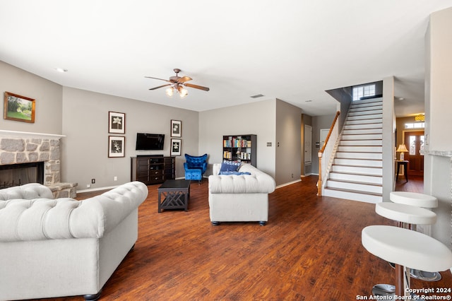 living room featuring a stone fireplace, ceiling fan, and hardwood / wood-style flooring