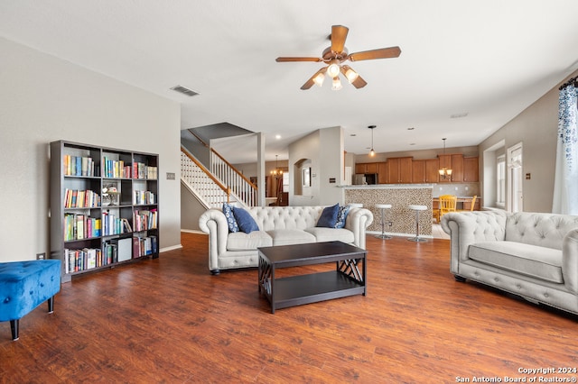 living room with ceiling fan with notable chandelier and dark wood-type flooring