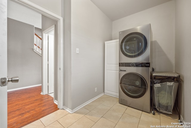 laundry room featuring stacked washer / dryer and light tile floors