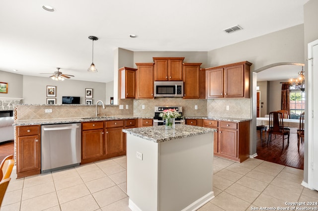 kitchen with ceiling fan with notable chandelier, hanging light fixtures, stainless steel appliances, and light tile flooring