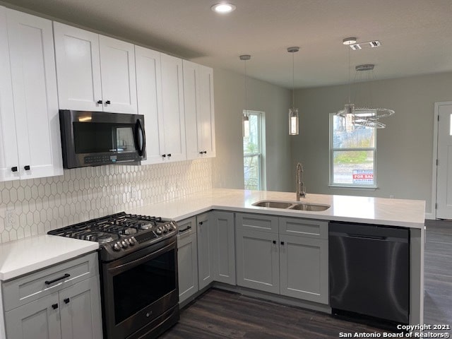 kitchen featuring sink, kitchen peninsula, hanging light fixtures, and black appliances