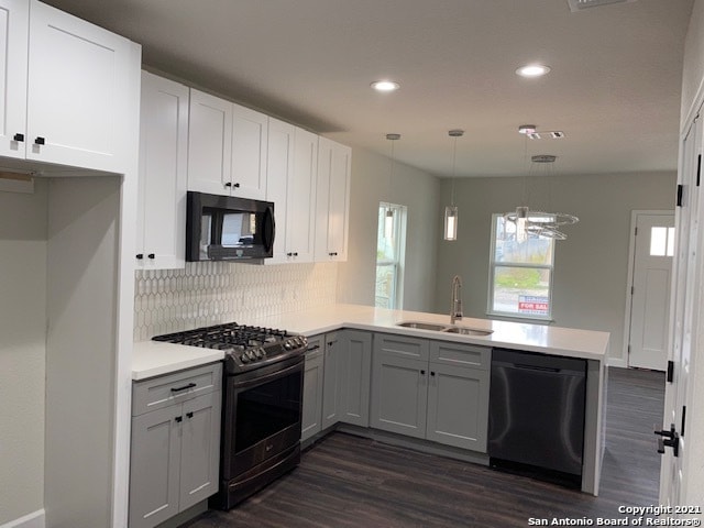 kitchen featuring kitchen peninsula, backsplash, black appliances, dark wood-type flooring, and pendant lighting