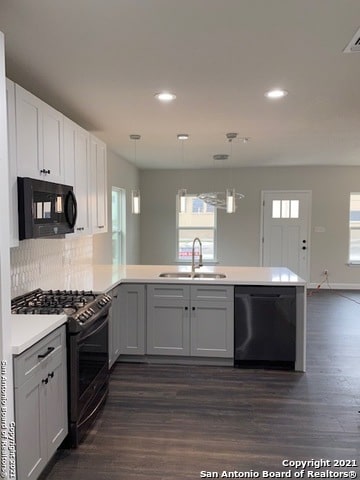 kitchen featuring a wealth of natural light, tasteful backsplash, black appliances, and sink