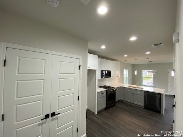 kitchen featuring dark hardwood / wood-style floors, black appliances, kitchen peninsula, sink, and tasteful backsplash