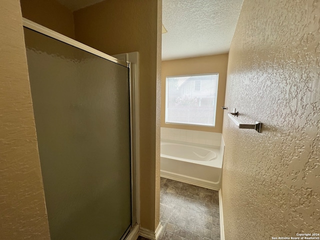 bathroom featuring a textured ceiling and separate shower and tub