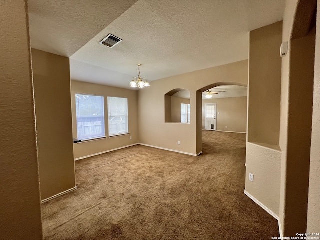 unfurnished room with a textured ceiling, ceiling fan with notable chandelier, and carpet flooring