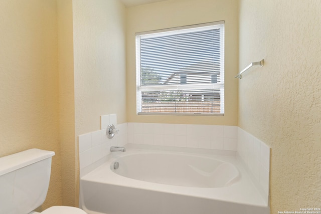 bathroom with a tub to relax in and toilet