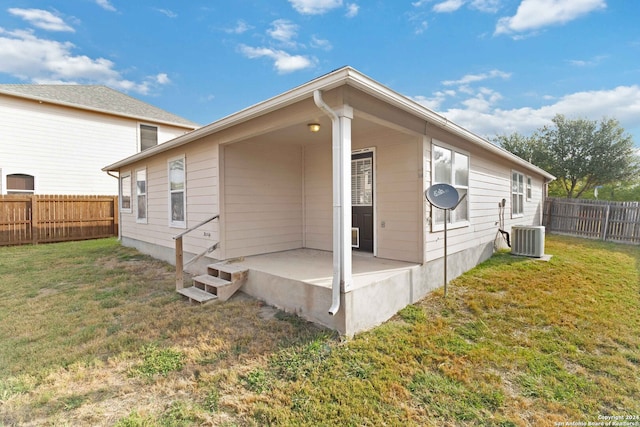 back of property featuring cooling unit and a yard