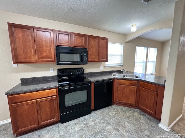 kitchen with kitchen peninsula, black appliances, a textured ceiling, and sink