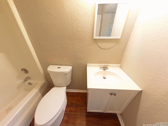 full bathroom featuring washtub / shower combination, oversized vanity, hardwood / wood-style flooring, and toilet