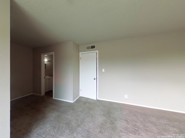 spare room with dark carpet and a textured ceiling