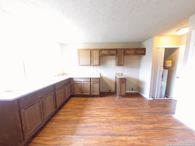 kitchen featuring a textured ceiling, water heater, and hardwood / wood-style floors