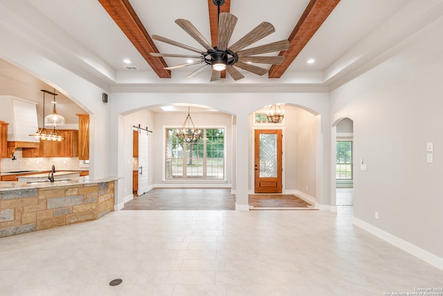 unfurnished living room featuring a healthy amount of sunlight, sink, ceiling fan with notable chandelier, and hardwood / wood-style flooring