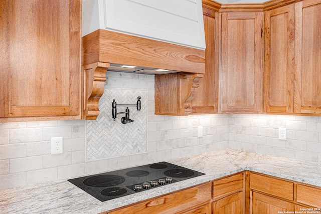 kitchen featuring backsplash, electric stovetop, light stone countertops, and custom range hood