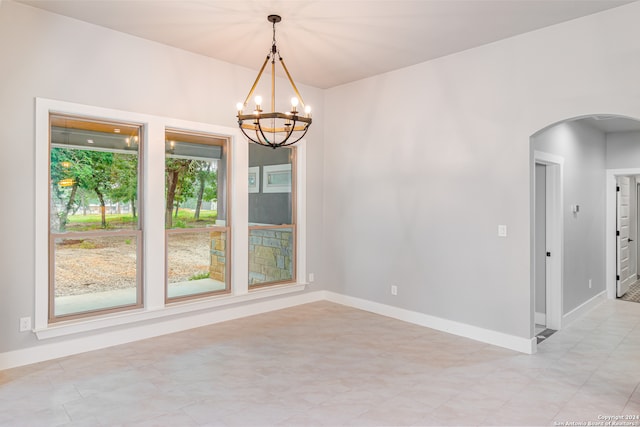 tiled spare room with an inviting chandelier