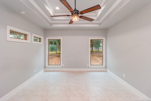 tiled empty room with ceiling fan and a raised ceiling