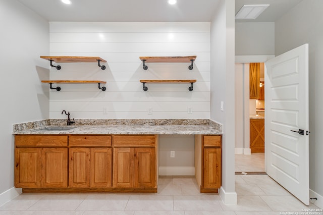 interior space with light stone countertops, sink, and light tile flooring