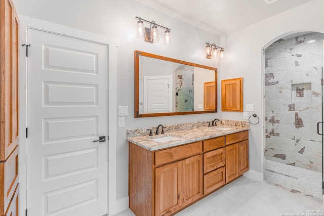 bathroom with dual bowl vanity, tile floors, and a shower with door