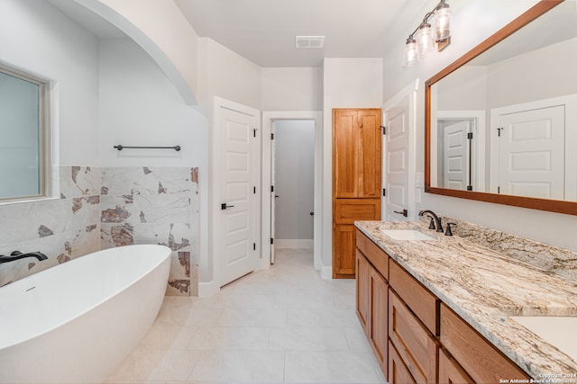 bathroom with tile walls, tile floors, double vanity, and a bath