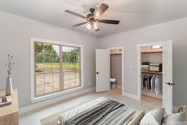 tiled bedroom featuring a closet, ceiling fan, and a walk in closet