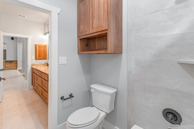 bathroom with tile flooring, toilet, and large vanity