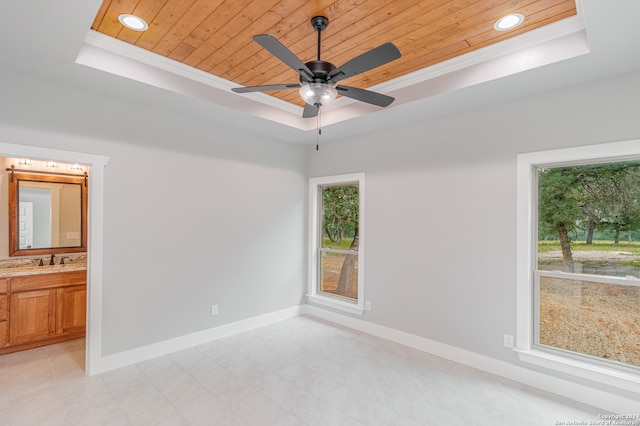 tiled empty room featuring ceiling fan, wooden ceiling, and a tray ceiling