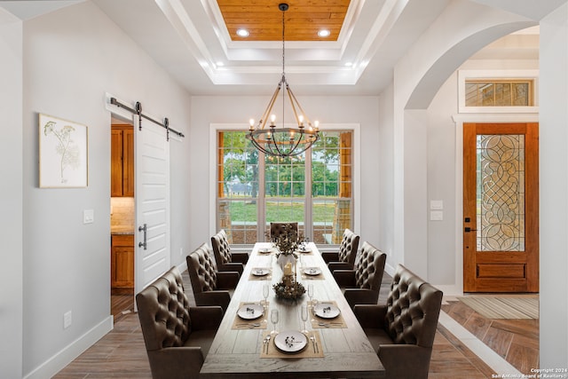 dining area with an inviting chandelier, a barn door, and a tray ceiling